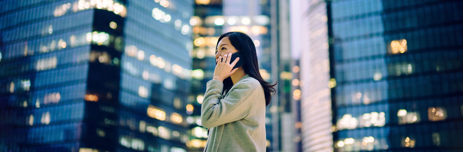 Frau mit Handy vor Hochhaus